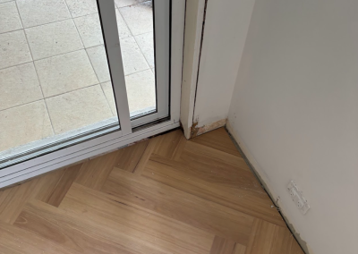 Laminate herringbone flooring meeting a tiled area by sliding doors, George Hall Sydney