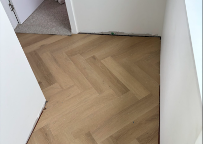 Laminate herringbone flooring laid along a white wall in a Bangor home, Sydney